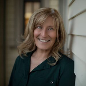 A woman standing in front of a wall smiling.